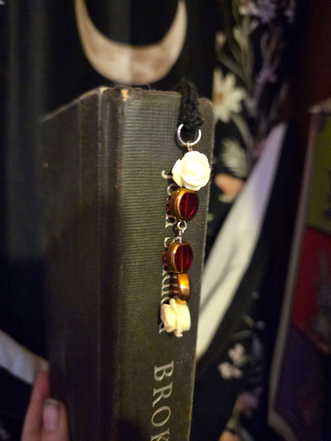 Bookmark with decorative elements hanging from a book, showcasing its beautiful design and functionality.