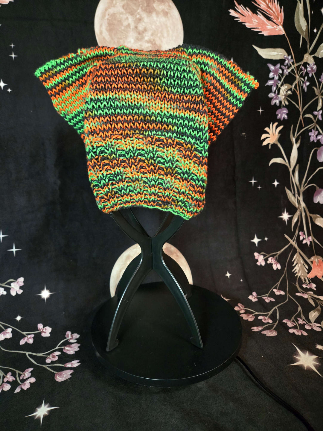 Colorful Cat Hats displayed on a stand with a floral background, showcasing the unique knitted pattern.